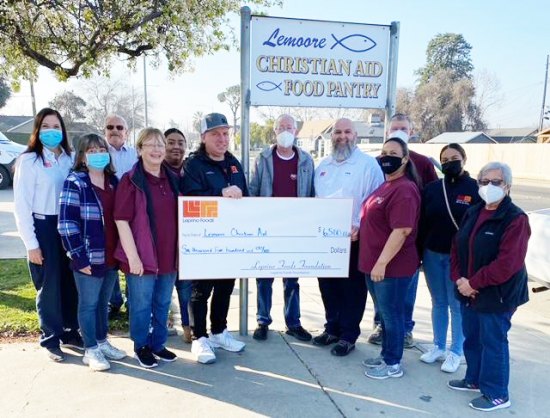 Lemoore Christian Aid's Nick Francu, along with volunteers, accept a $6,500 check from Leprino Foods officials, including Anna Nicks, Larry Jones, Tom Christensen, and Celeste Corona.
